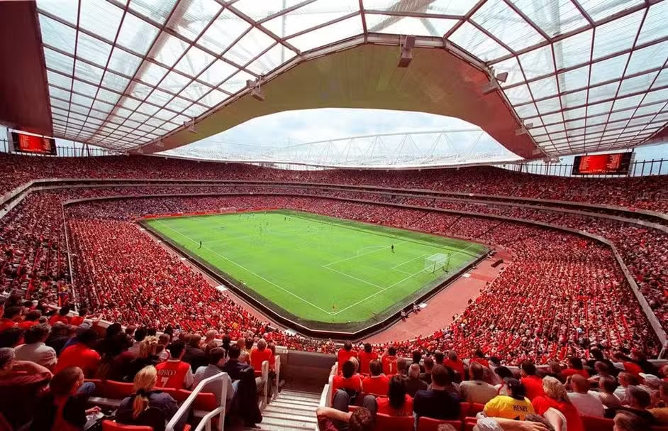 Duffy - Strategy Crowd fills a large modern stadium, watching a soccer match on a bright green field under a glass roof.