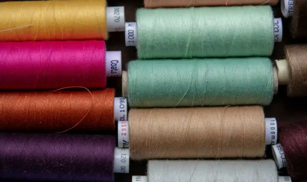 Colorful spools of thread arranged in rows.