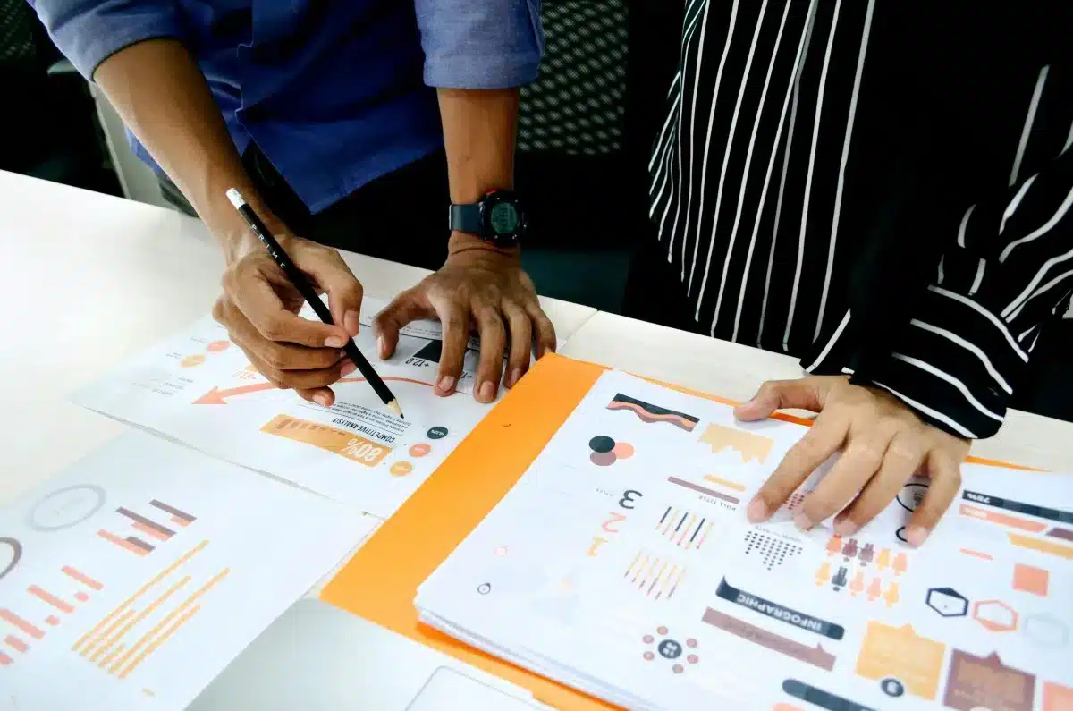 TonbridgeSchool-TheChallenge Two people reviewing and discussing colorful charts and graphs on printed sheets at a desk.